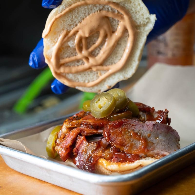 A jar of Alabama white sauce next to smoked chicken